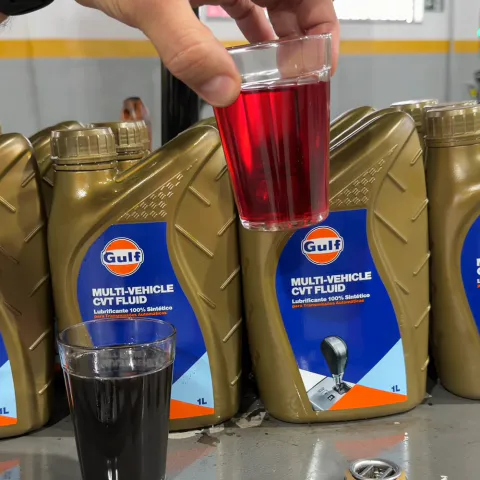Copo de fluido novo, vermelho, erguido acima de um copo de fluido usado, escuro